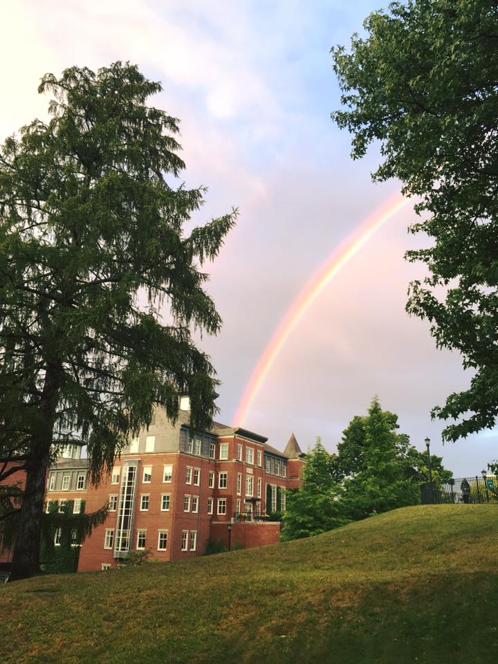 Photograph of a building at Holy Cross with a rainbow in the sky.