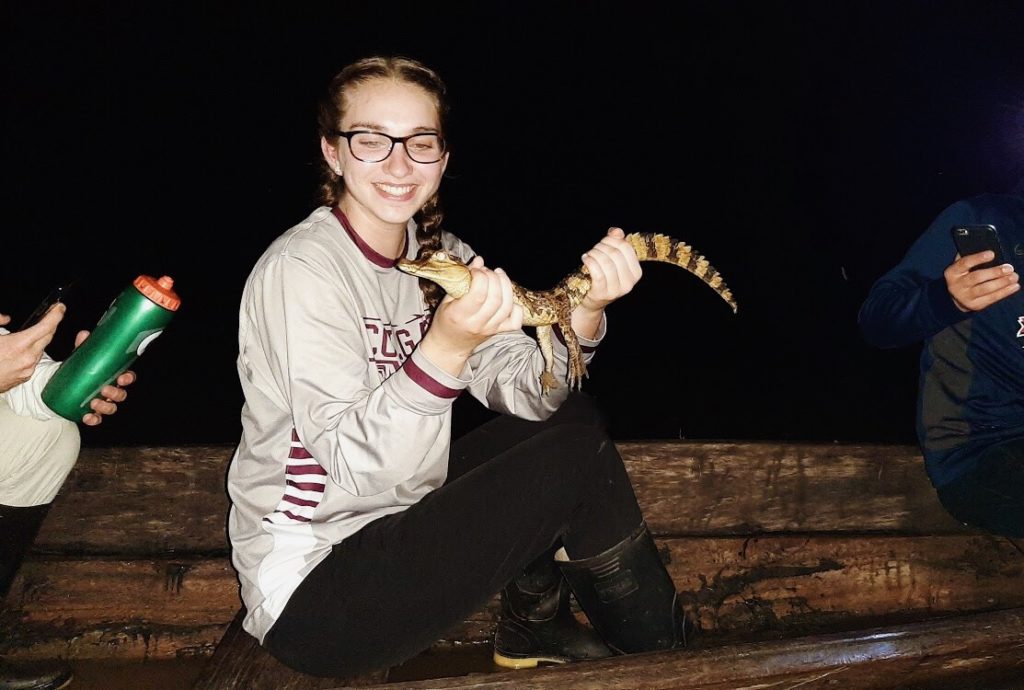 Sarah in a canoe holding an alligator. 