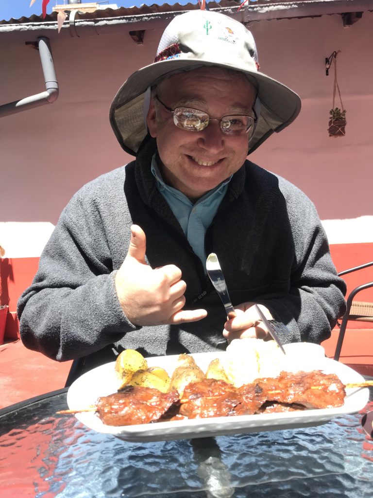 Sarah's dad excited to eat the anticuchos which are on the plate in front of him